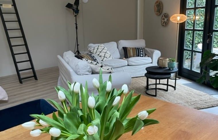 Binnenruimte van Huisje in Tienhoven, vakantiehuis in Tienhoven, Utrecht, met comfortabele zithoek en bloemen.