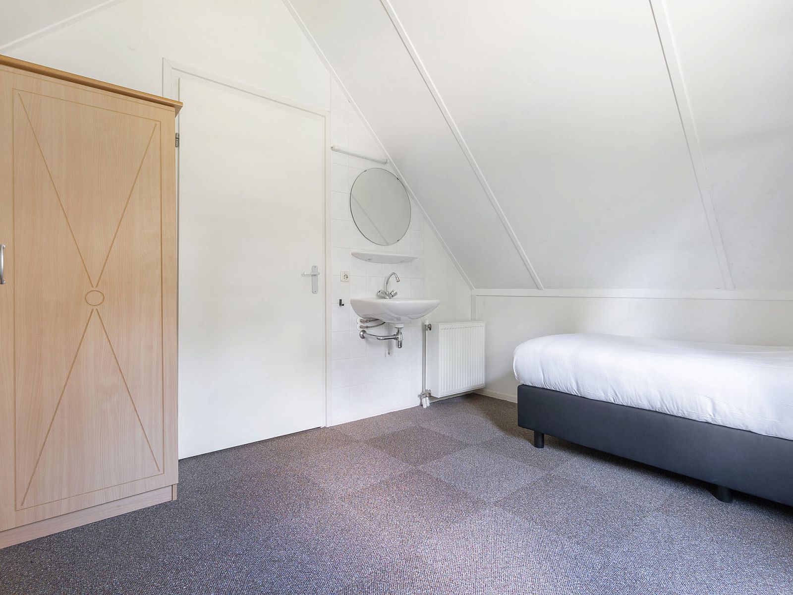 Sfeervolle slaapkamer in Vakantiewoning Beukenrode, Doorn, Utrechtse Heuvelrug. Rustgevende binnenruimte met comfortabel bed en moderne wasbak.