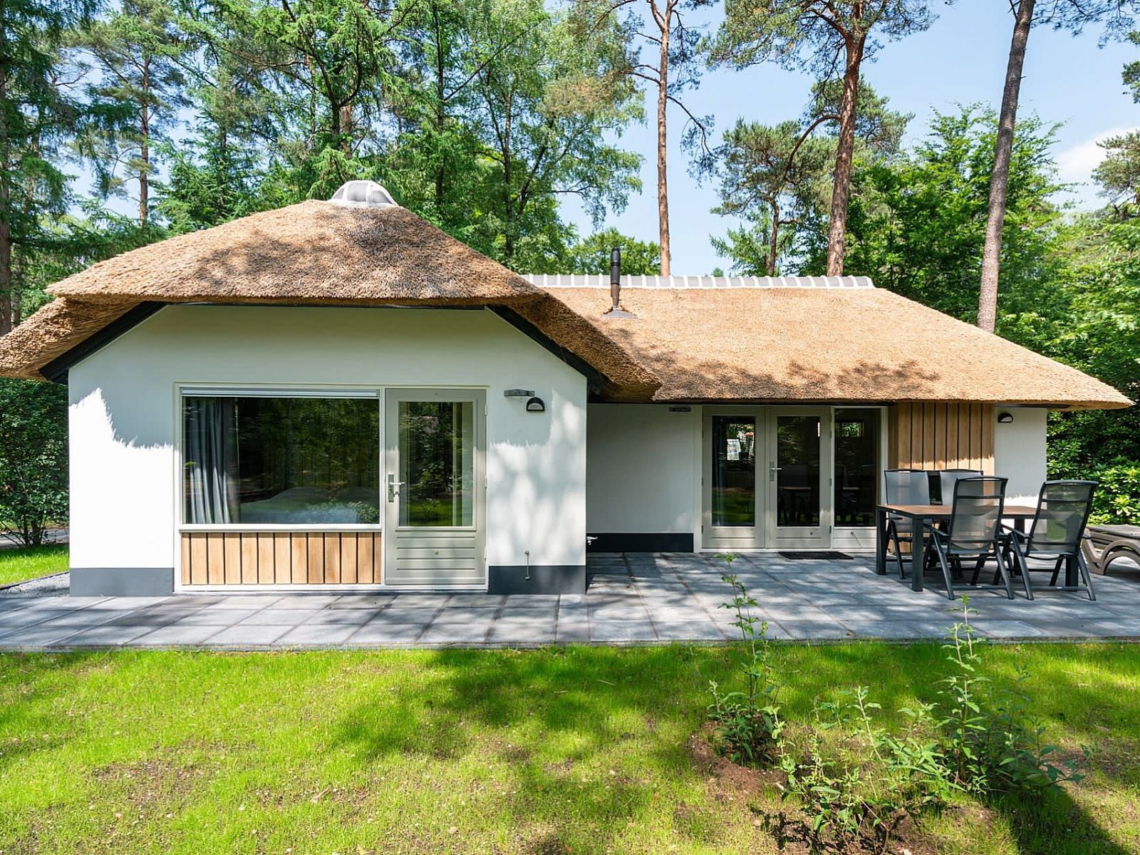 Bungalow Dennenburg in Doorn, Utrechtse Heuvelrug with thatched roof and terrace in green surroundings.