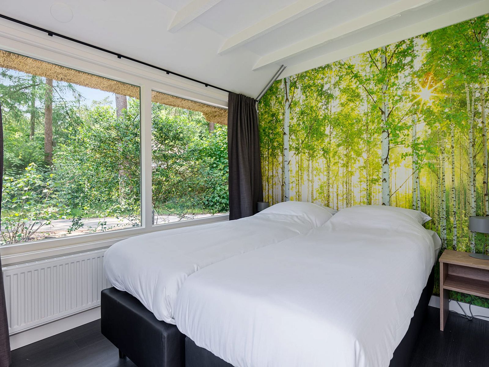 Bedroom with double bed and forest wallpaper in Bungalow Dennenburg, Doorn, Utrechtse Heuvelrug.