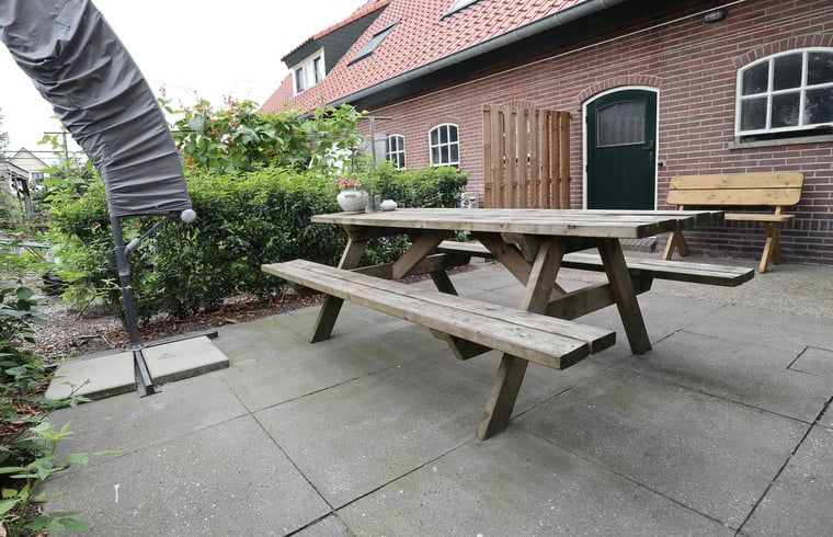 Gezellige woonkamer in Vakantiehuisje in Achterveld, Utrechtse Heuvelrug, met houten balken en comfortabele zitruimte.