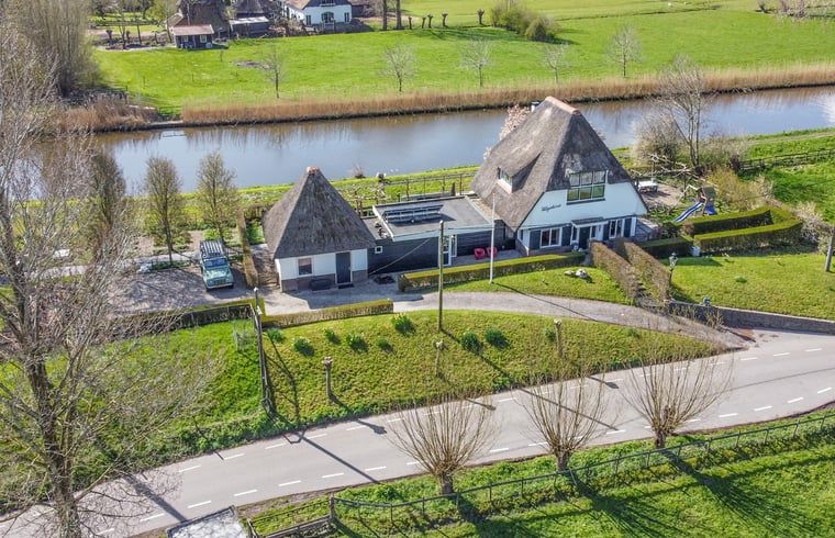 Luchtfoto van Vakantiehuisje in Hekendorp, Utrecht, met rieten daken en uitzicht op een rustige rivier en groene omgeving.
