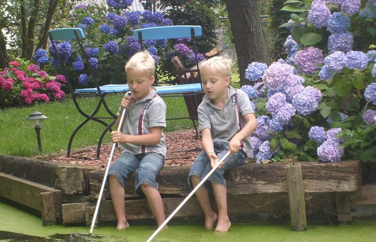 Children playing by the water at Huisje in Zegveld, vacation home in Zegveld, Utrecht. Family-friendly environment with lots of nature.