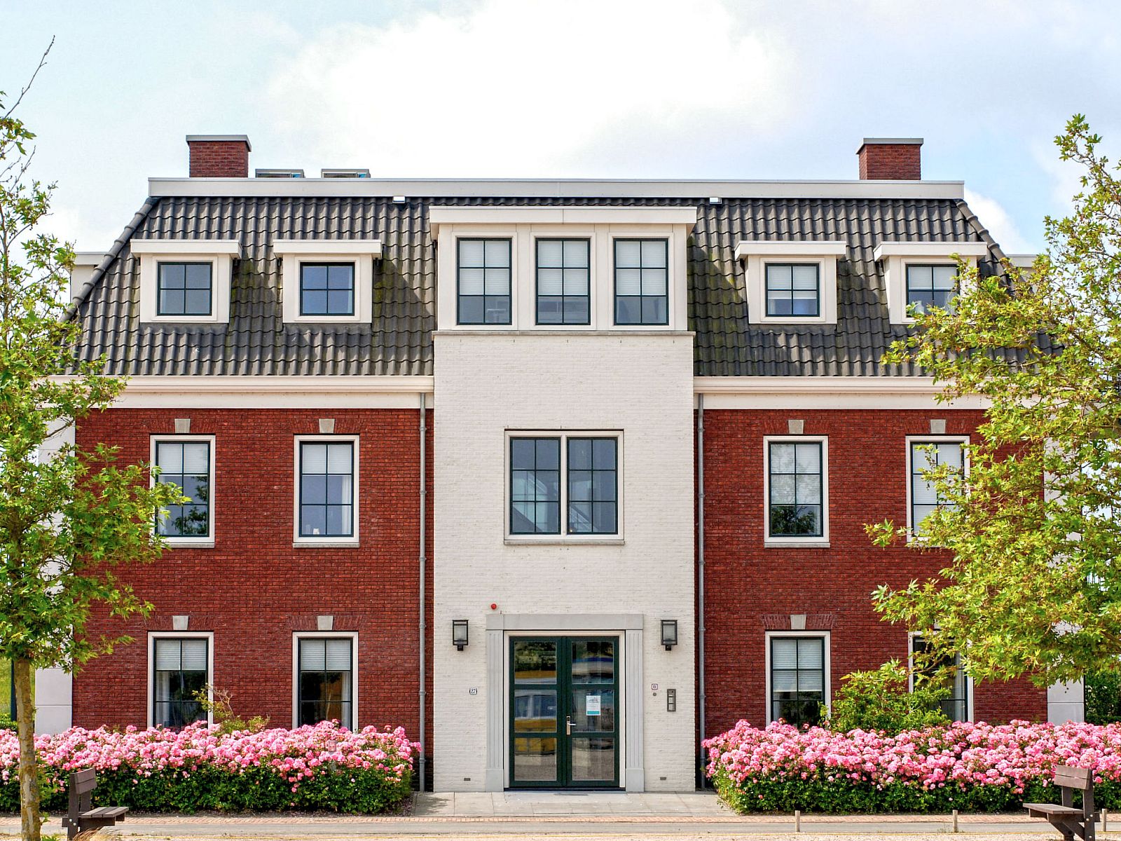 Charmanter Aussenbereich des Apartments Ganuenta in Colijnsplaat, Nord-Beveland, mit roten Ziegeln und bluehenden Blumen.