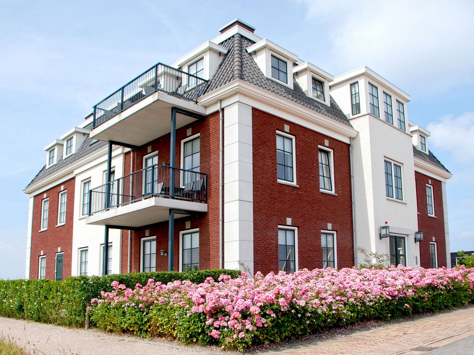 Seitenansicht des Apartments Ganuenta in Colijnsplaat, Nord-Beveland, mit Balkon und bunten Blumenbeeten.