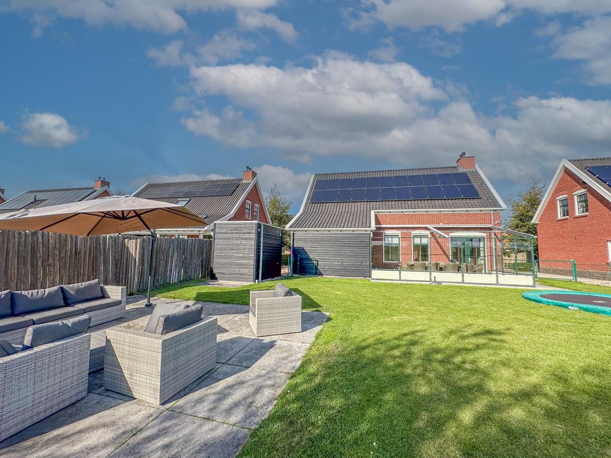 Ruim terras bij Dune Design 39 vakantiehuis in Colijnsplaat, Noord-Beveland, met comfortabele zithoek en groene tuin in zonnige omgeving.