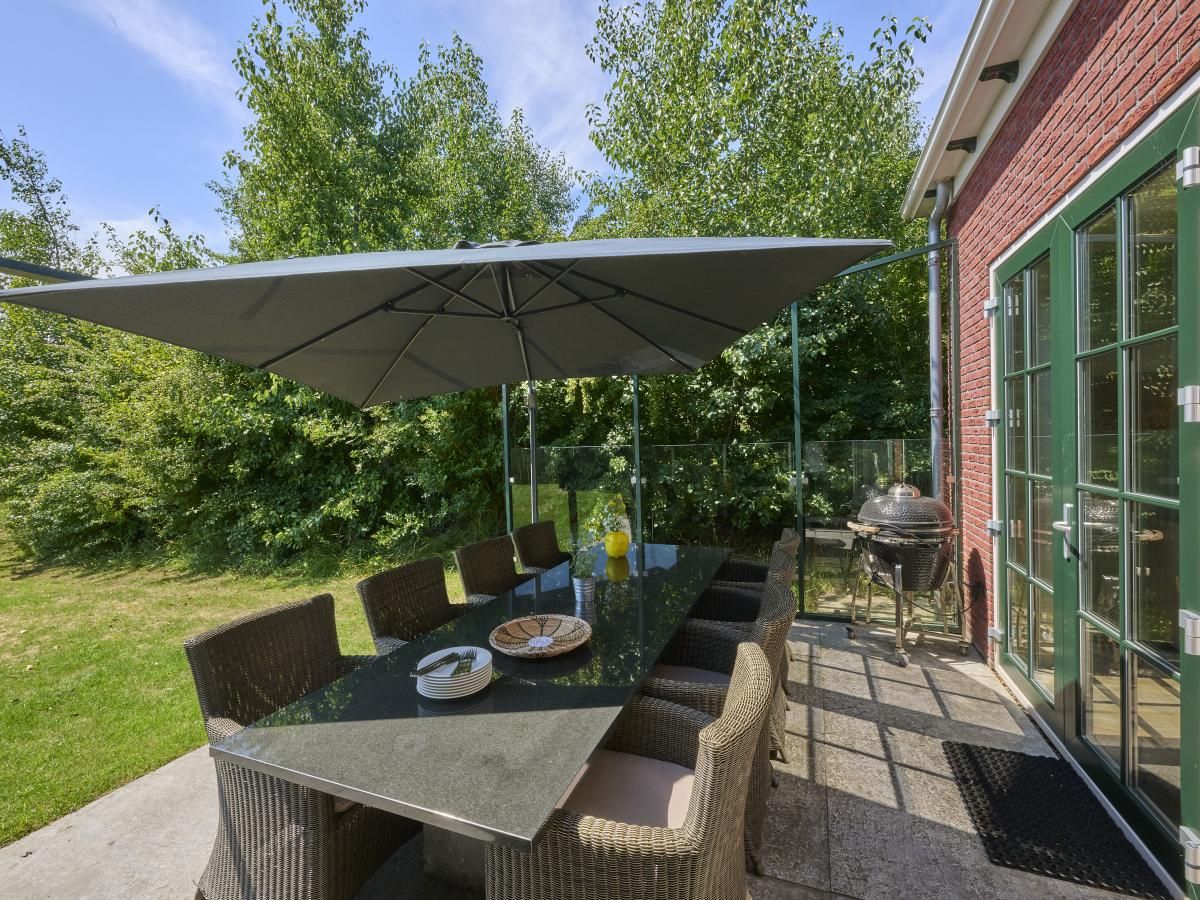 Gezellig terras bij Ocean Ease 49 in Colijnsplaat, Noord-Beveland, met ruime eettafel en parasol voor buitenmaaltijden.