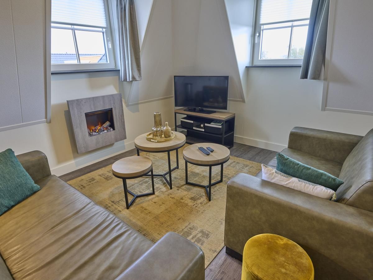 Cozy living room of Sauna Zee 27H in Colijnsplaat, North Beveland, with comfortable sofas and a modern fireplace.