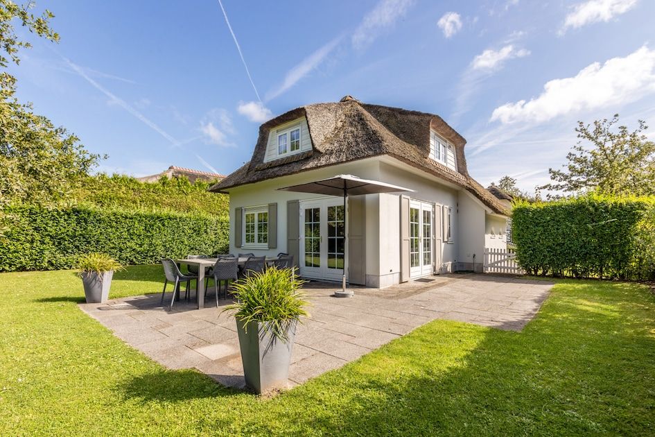 Villa R8B in Kamperland, Noord-Beveland biedt een charmant vakantiehuis met rieten dak en zonovergoten terras in groene omgeving.