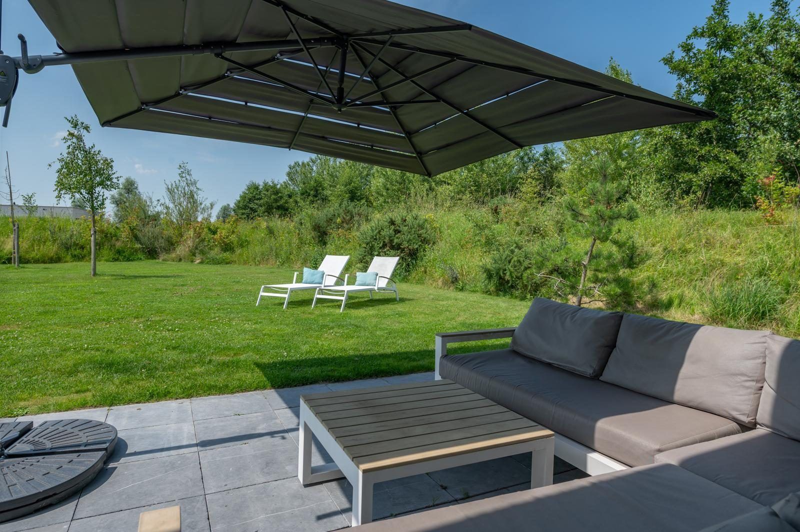 Luxurioese Lounge auf der Terrasse des Ferienhauses Waterline 25 | De Groote Duynen in Kamperland, Noord-Beveland, mit Blick auf den Garten.