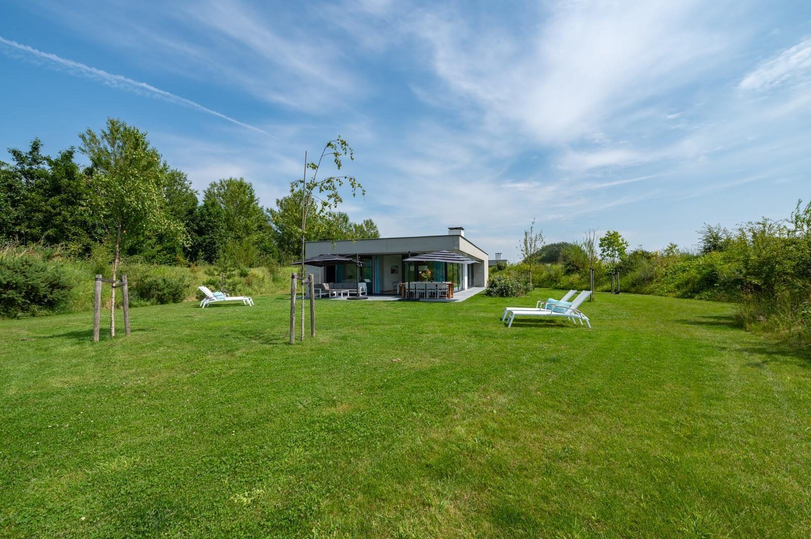 Geraeumiger Garten am Waterline 25 | De Groote Duynen, Ferienhaus in Kamperland, Noord-Beveland, mit Liegestuehlen und gruener Landschaft.