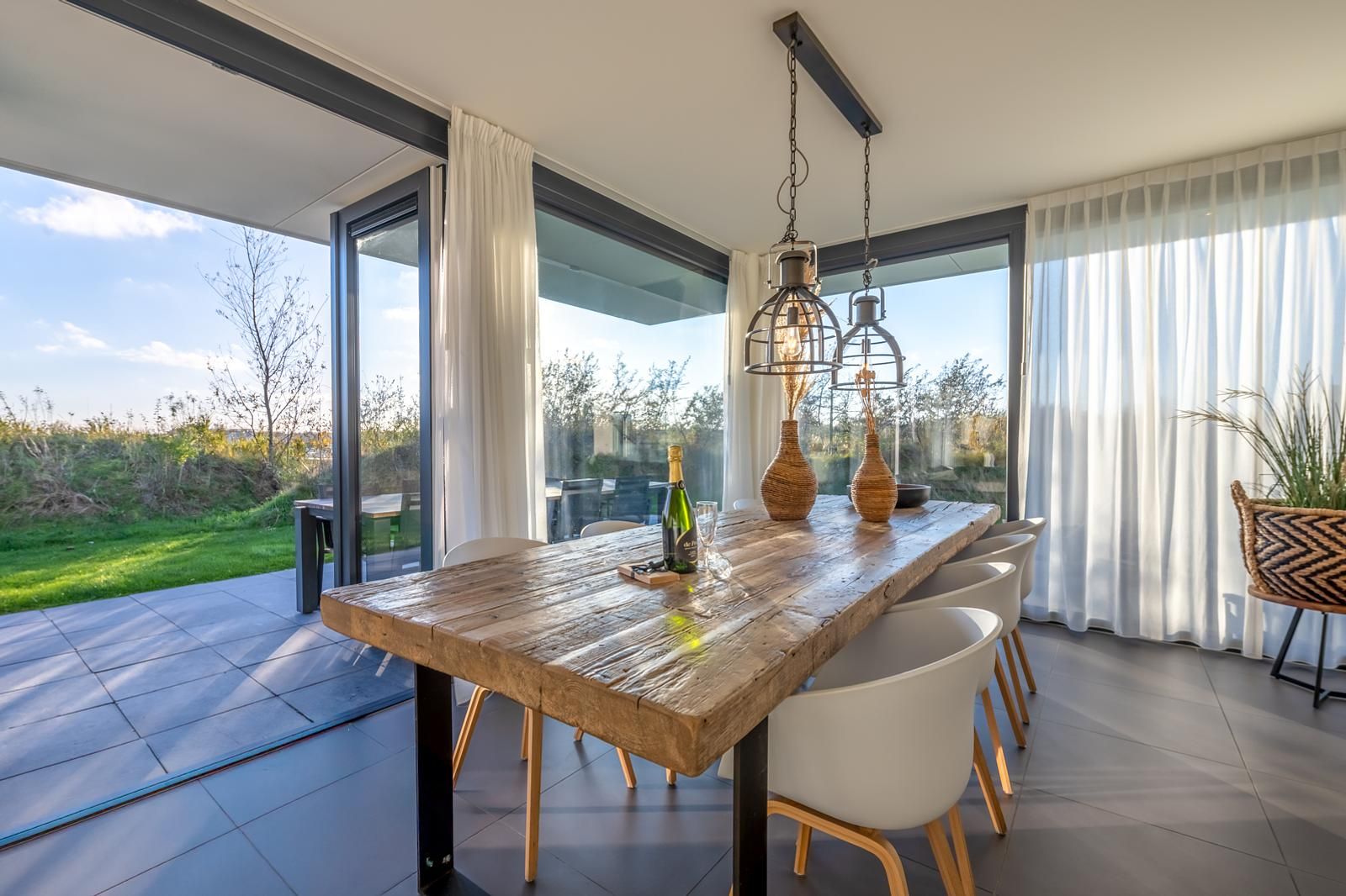 Ruime eetruimte in Duinvallei 39, De Groote Duynen, Kamperland, met moderne stoelen en een glazen wand.