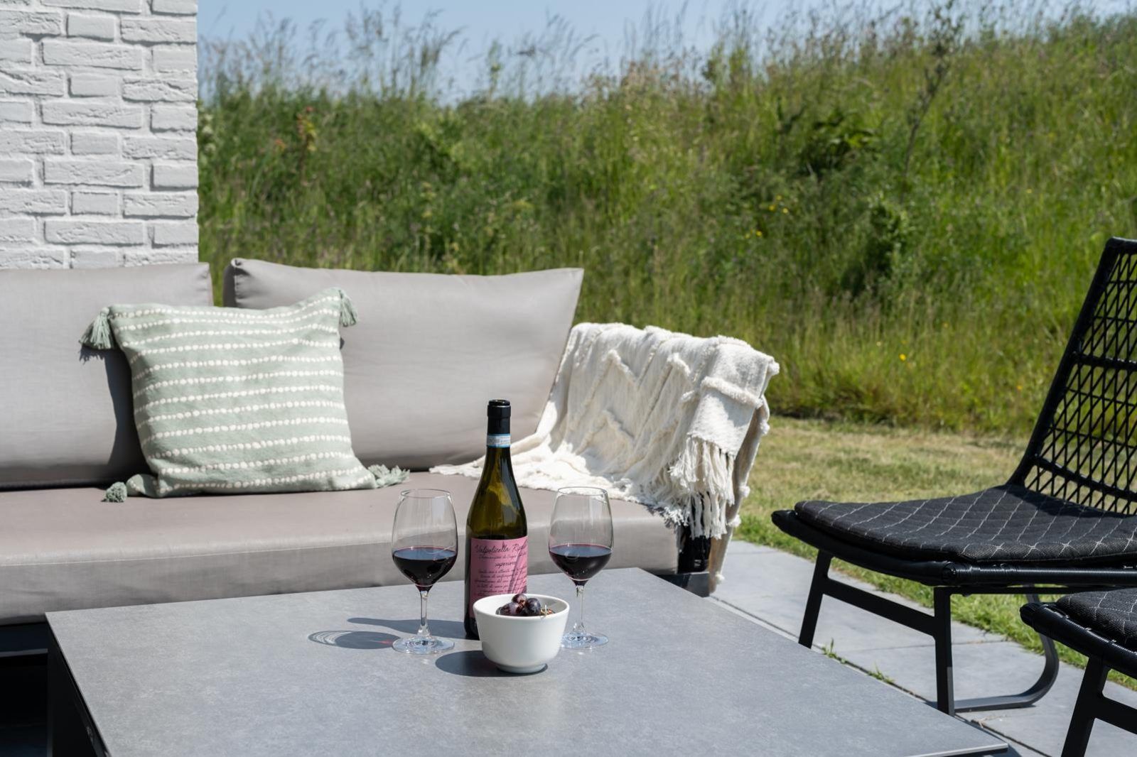 Detail van het terras in Duinvallei 39, De Groote Duynen, Kamperland, met een fles wijn en glazen.