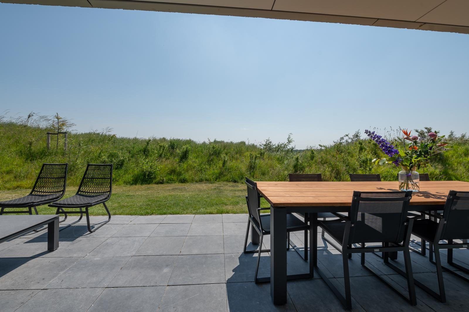 Buitenruimte van Duinvallei 39, De Groote Duynen, Kamperland, met een eettafel en uitzicht op de natuur.