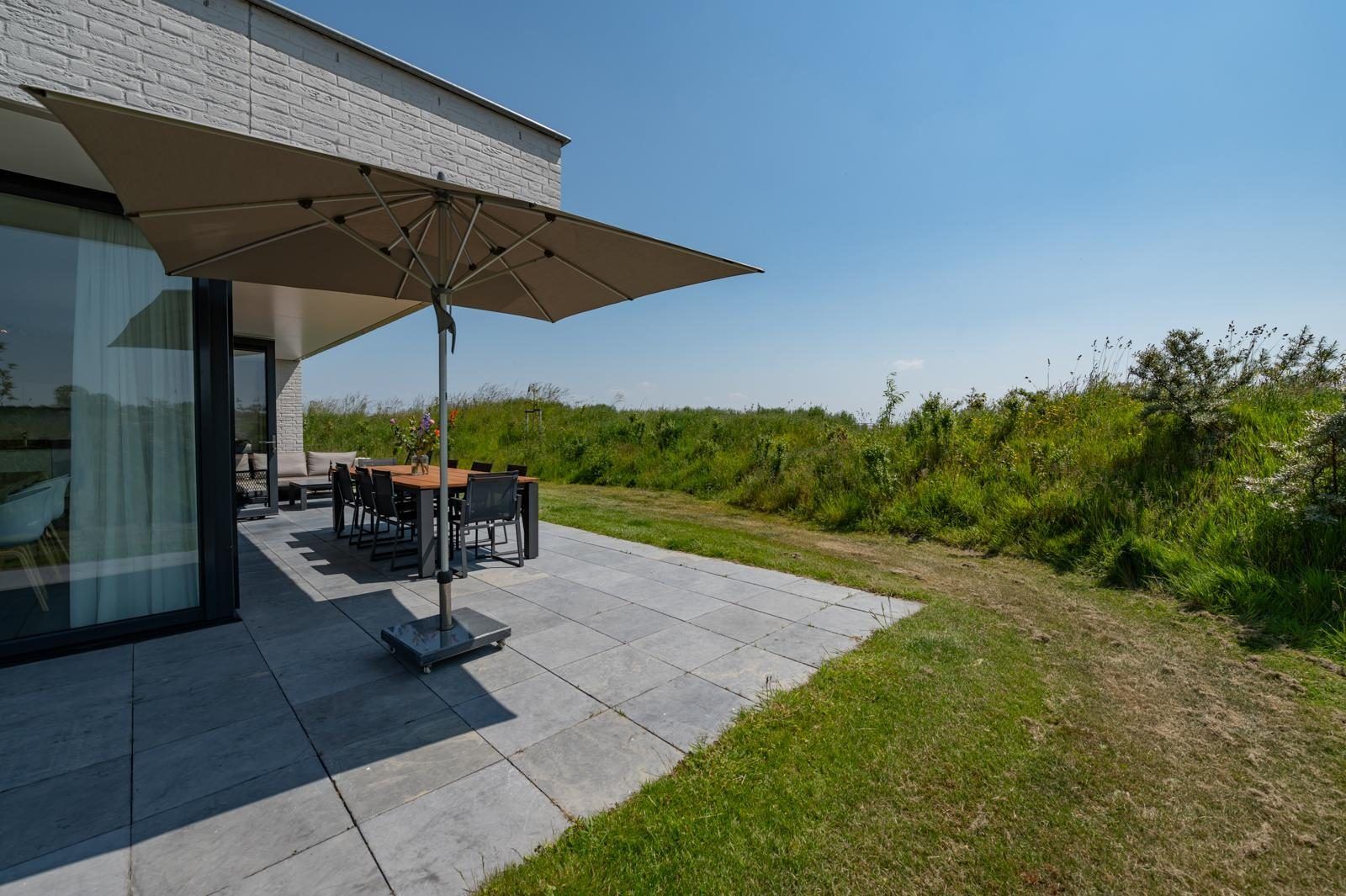 Schaduwrijke plek op het terras van Duinvallei 39, De Groote Duynen, Kamperland, met een grote parasol.