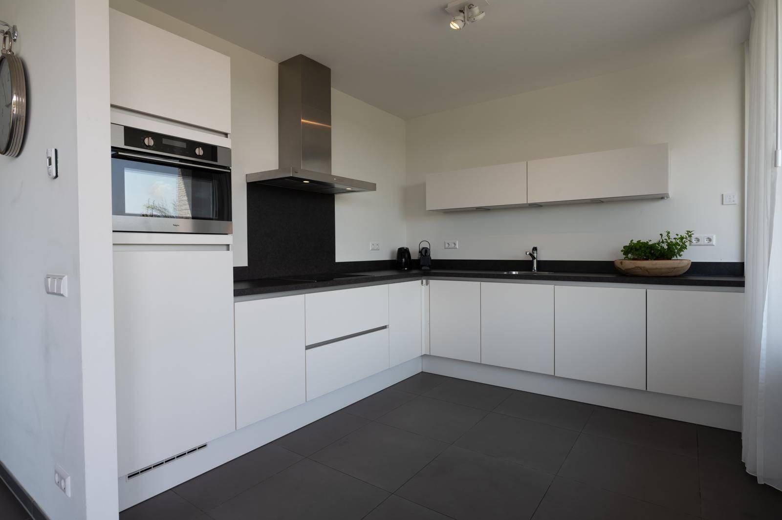 Moderne keuken in Duinvallei 39, De Groote Duynen, Kamperland, met strakke witte kasten en apparatuur.