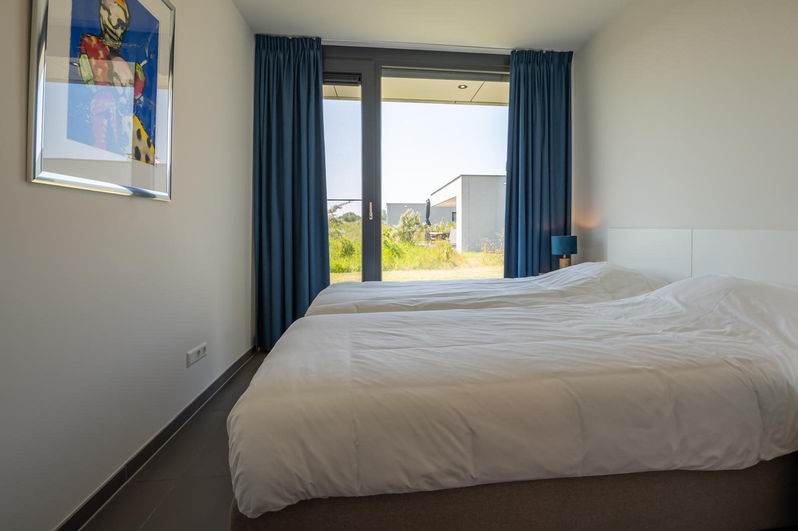 Derde slaapkamer in Duinvallei 39, De Groote Duynen, Kamperland, met comfortabele bedden en een schilderij.