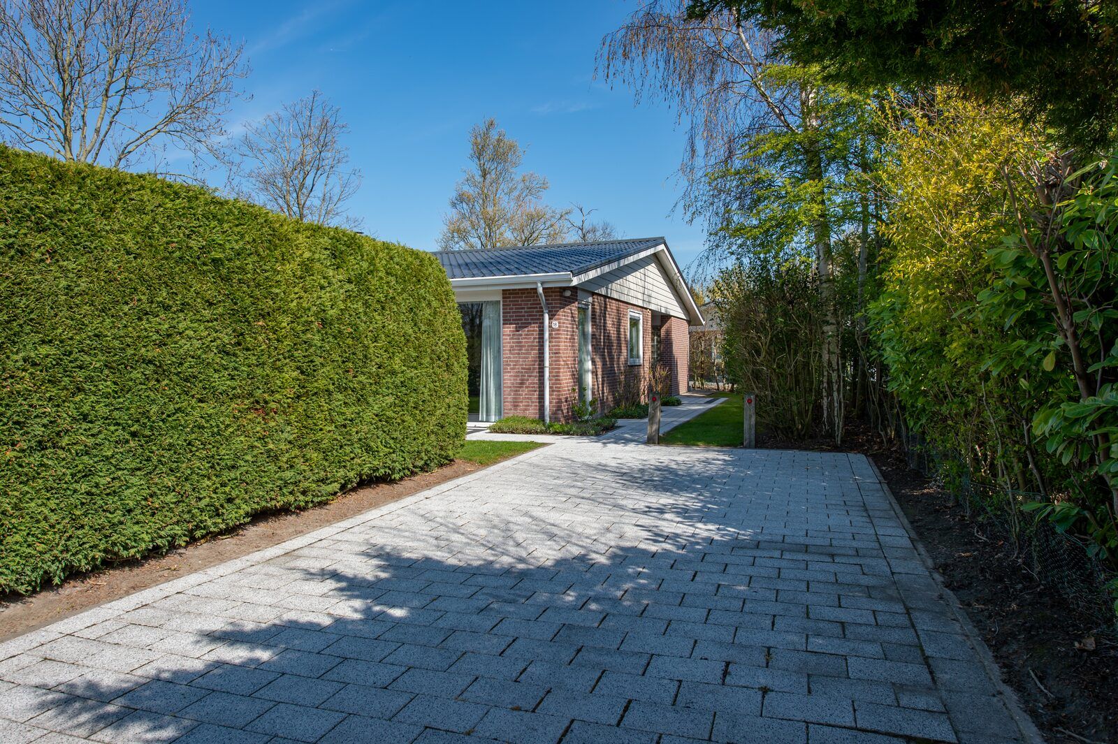 Oprit en entree Cypressenlaan 18, vakantiehuis in Kamperland, omgeven door groen.