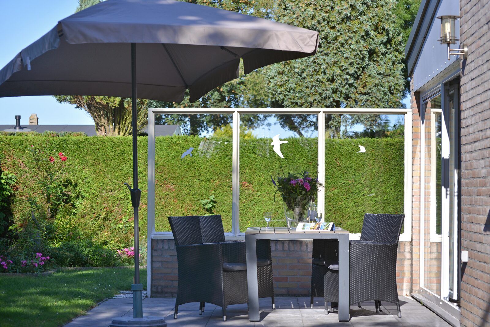 Sonniger Garten mit Terrasse und Sonnenschirm im Ferienhaus Saturnuslaan 14 Rancho Grande in Kamperland, Noord-Beveland, Zeeland.