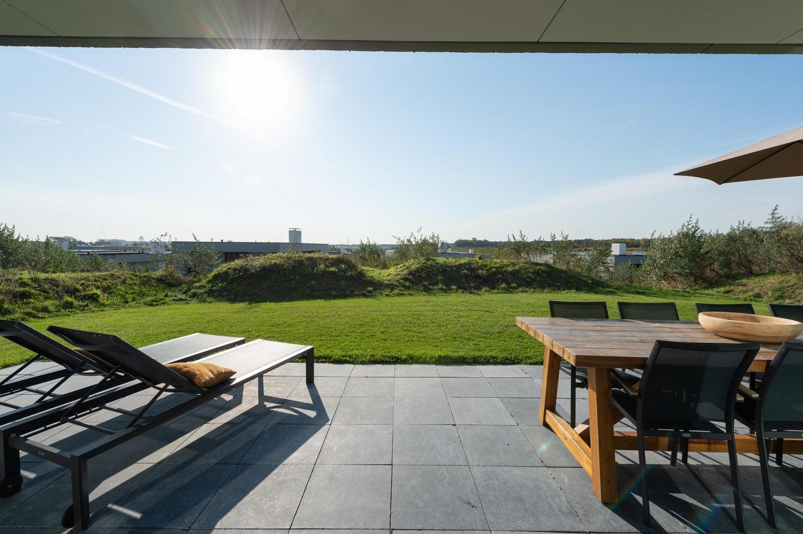 Grosse Terrasse am Ferienhaus Duinvallei 43 in Kamperland, mit Esstisch und Liegestuehlen zum Entspannen.