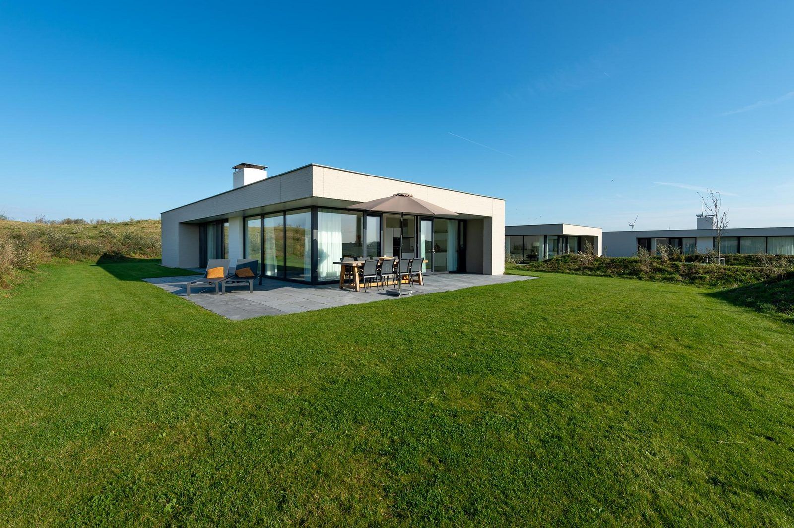 Rueckseite von Duinvallei 43, Ferienhaus in Kamperland, mit grosser Terrasse und gruenem Garten.