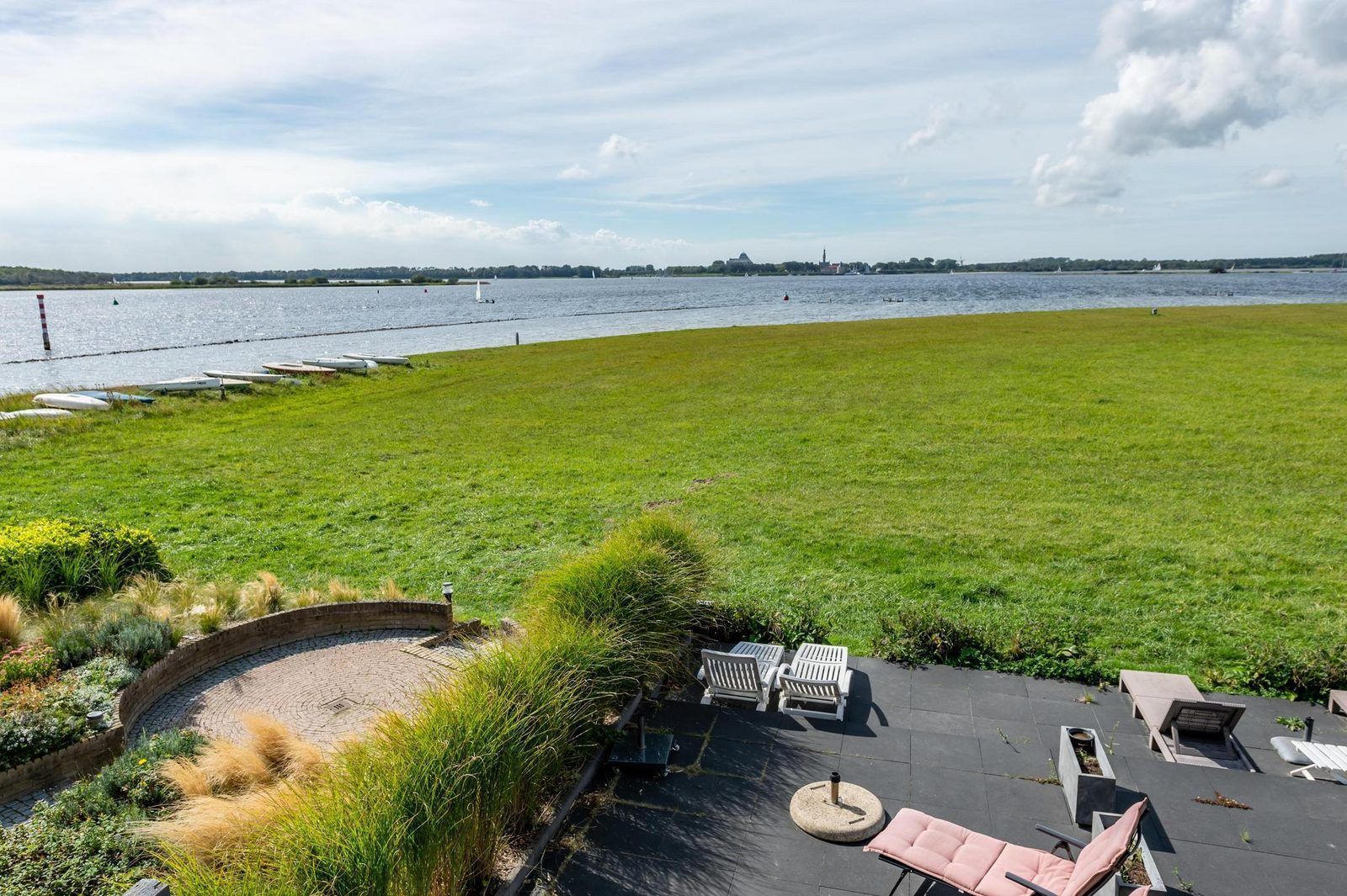 Terras van VZ2312 Vakantiehuis in Kamperland met ligstoelen en uitzicht op het meer, Noord-Beveland, Zeeland.
