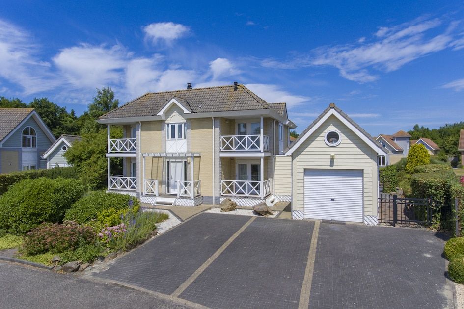 Villa R10B in Kamperland, ein charmantes Ferienhaus in Nord-Beveland, Zeeland, mit einer einladenden Veranda und einem schoenen Garten.