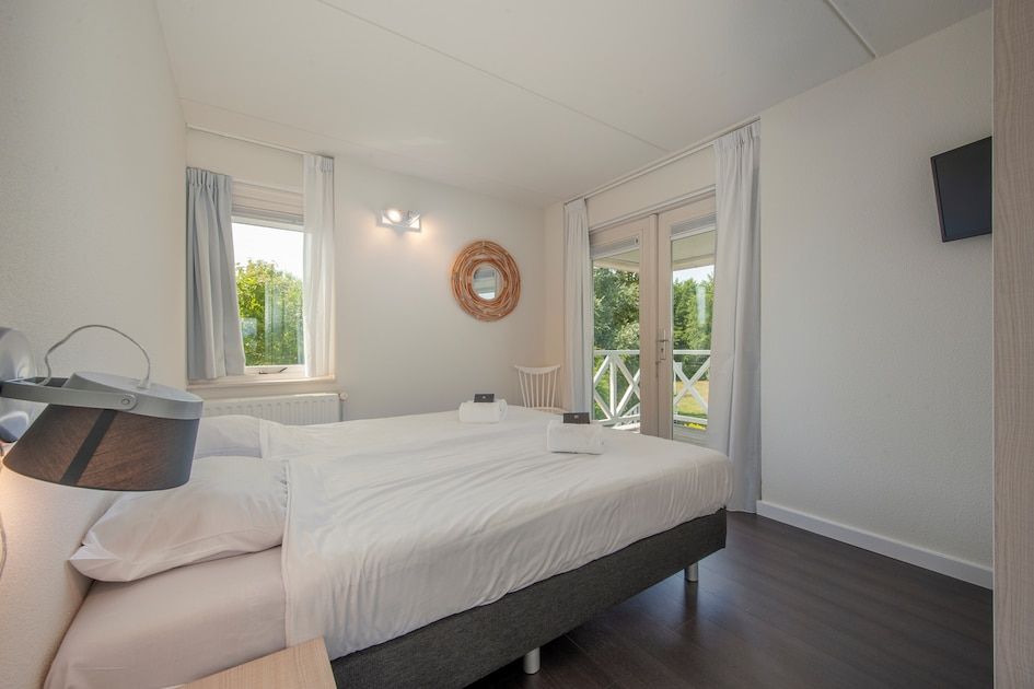 Attraktives Schlafzimmer in der Villa R10B, einem Ferienhaus in Kamperland, Noord-Beveland, mit Blick auf die gruene Umgebung von Zeeland.