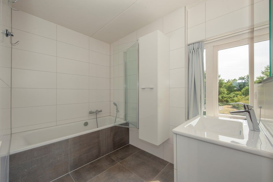 Modernes Badezimmer in der Villa R10B, Ferienhaus in Kamperland, Zeeland, mit Blick auf die gruene Umgebung.