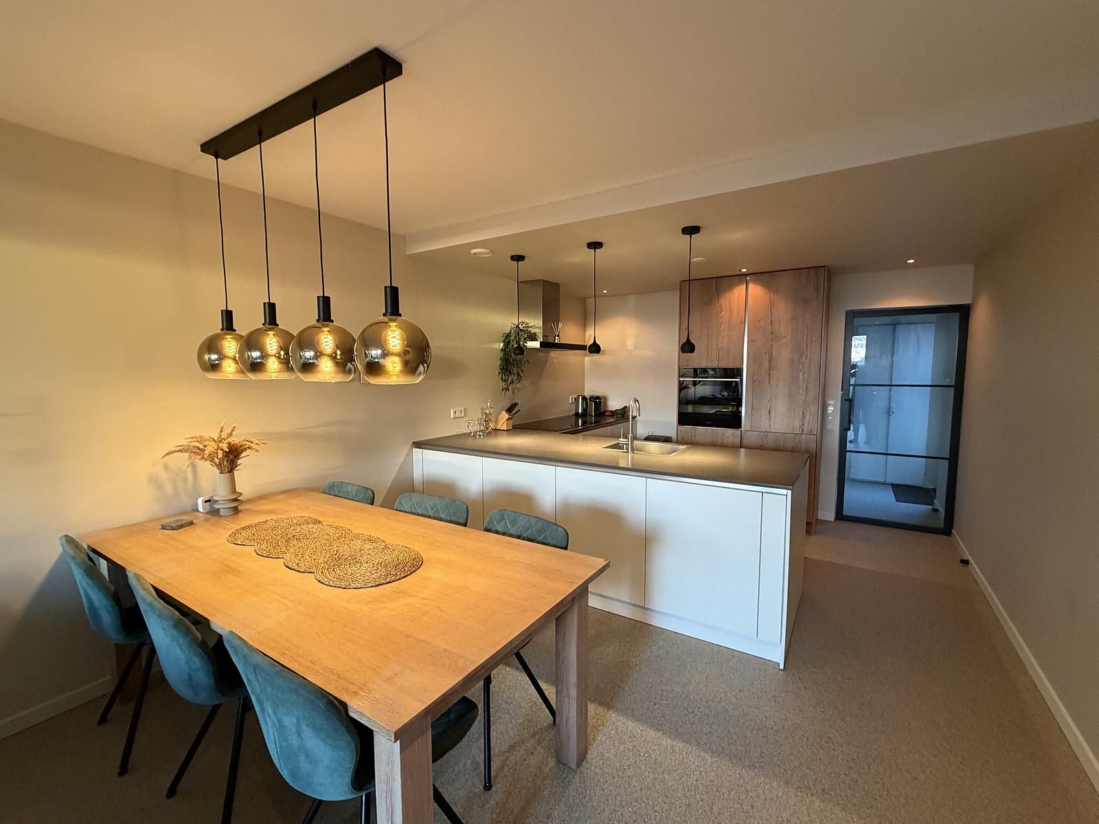 Moderne keuken en eetruimte in Havenweg 24, een vakantiehuis in Kamperland, Noord-Beveland, Zeeland met stijlvolle lampen en houten tafel.