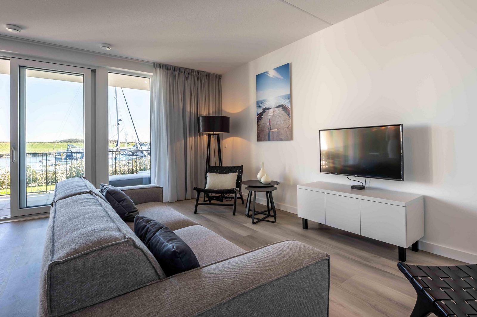 Moderne zithoek in vakantiehuis Harbour Loft 1E, Noord-Beveland, met uitzicht op zeilboten.