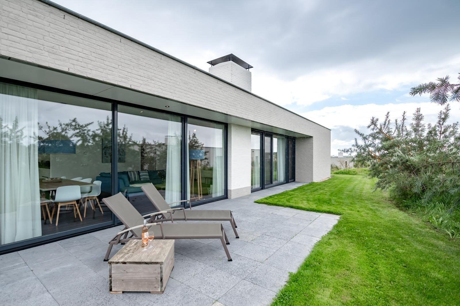 Geraeumige Terrasse des Ferienhauses Duinvallei 09 in Kamperland, Noord-Beveland, mit Liegestuehlen und gruener Umgebung.