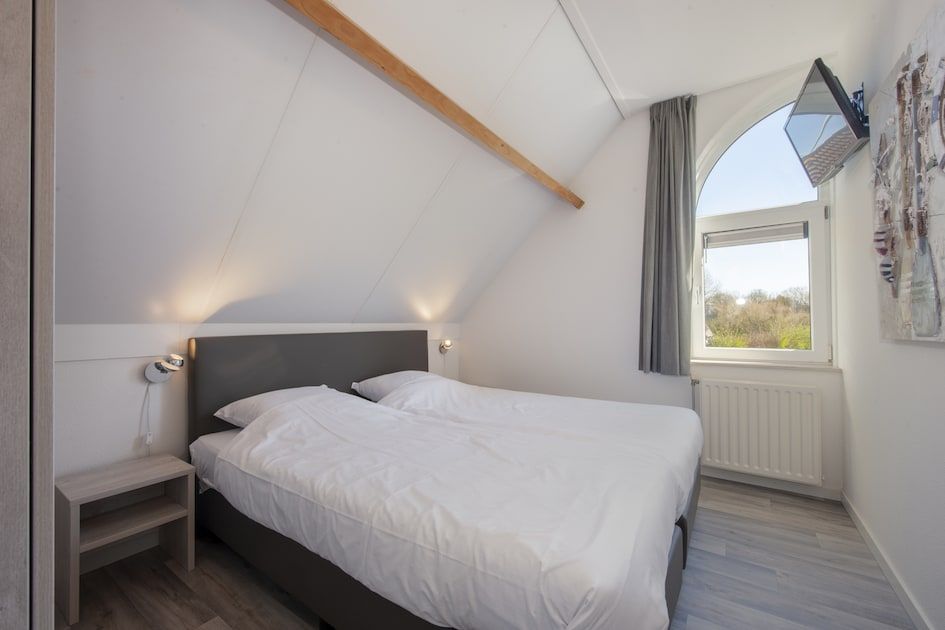 Helles und geraeumiges Schlafzimmer in der Villa R6A, einem Ferienhaus in Kamperland, Noord-Beveland, Zeeland, mit Blick auf die gruene Umgebung.