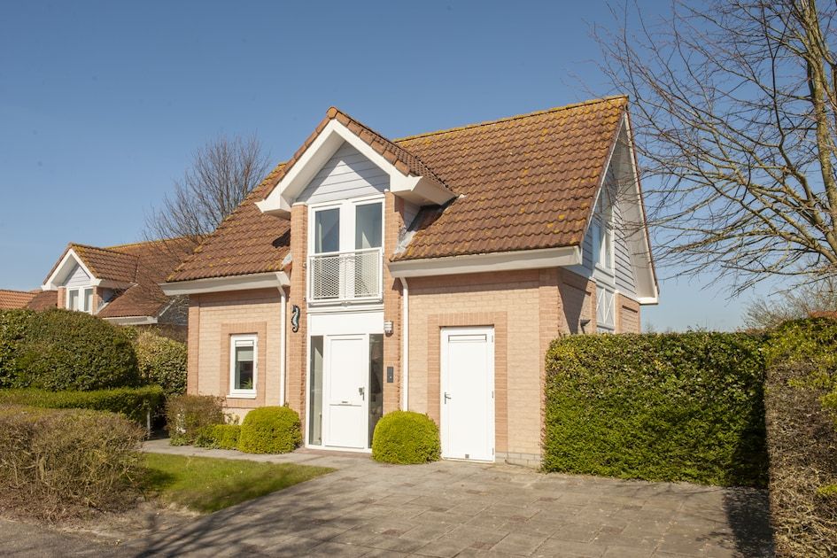 Modernes Badezimmer in der Villa R6A, einem Ferienhaus in Kamperland, Nord-Beveland, Zeeland, mit hellen Fliesen und einem bunten Duschvorhang.