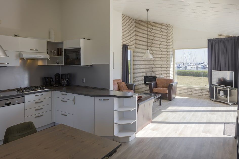 Helles Wohnzimmer und Kueche in BA-Bungalow, Kamperland, Noord-Beveland, Zeeland, mit Blick auf den Yachthafen und moderner Einrichtung.