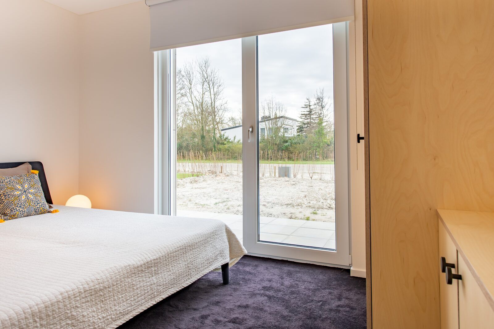 Schlafzimmer mit grossem Fenster in Schotsmanweg 16 | Zeeuws Goedt, Ferienhaus in Kamperland, Noord-Beveland mit Blick auf den Garten.