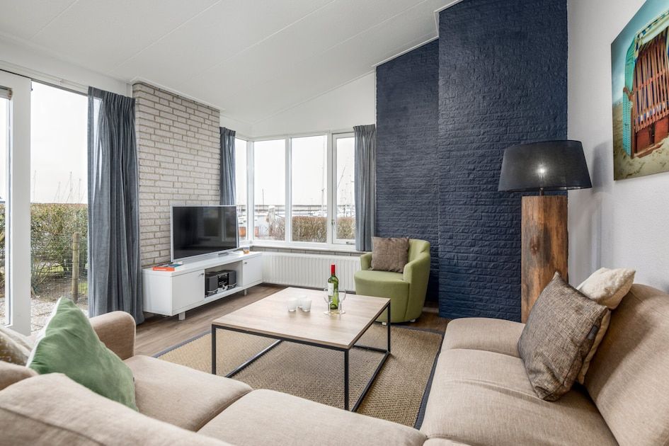 Cozy living room of RG Comfort bungalow in Kamperland, North Beveland with comfortable sofas and garden view.