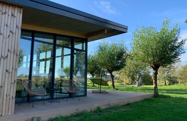 Terrace of vacation home in Kamperland with comfortable chairs and views of green surroundings in North Beveland, Zeeland.