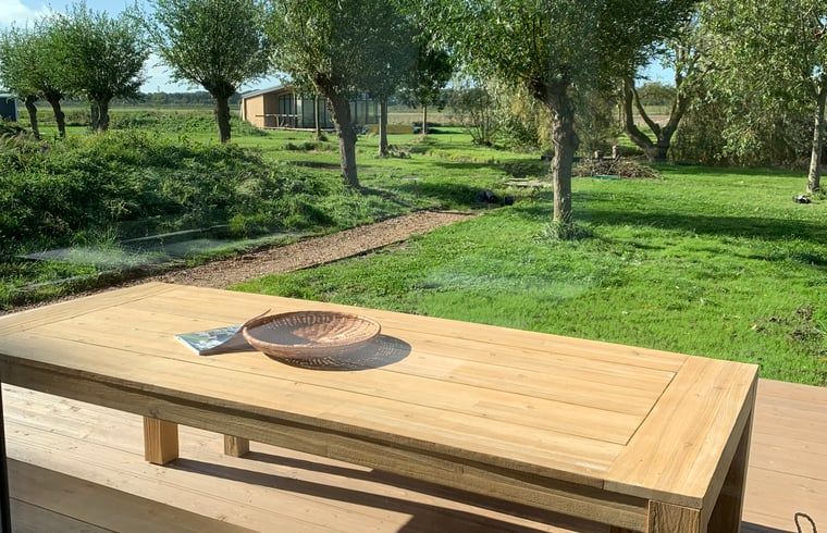 Wooden dining table on the terrace of vacation home in Kamperland overlooking nature in North Beveland, Zeeland.
