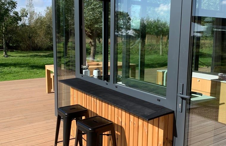 Outdoor terrace of vacation home in Kamperland with bar and stools, ideal for relaxation in North Beveland, Zeeland.