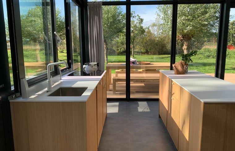 Modern kitchen in cottage in Kamperland overlooking terrace and nature in North Beveland, Zeeland.