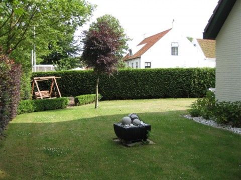 Spacious garden of Mi Casa, Burgh-Haamstede, with swing and green view, ideal for relaxation in Zeeland.