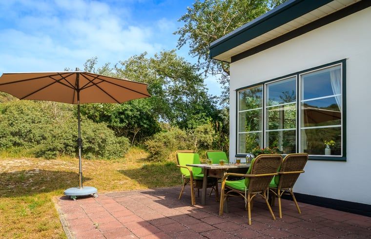 Sonnige Terrasse mit Sonnenschirm im Huisje in Burgh-Haamstede, ideal fuer ein Essen im Freien in Schouwen-Duiveland.