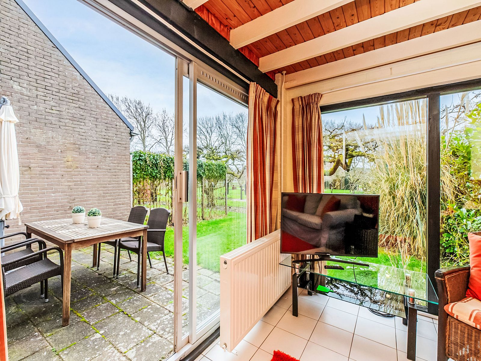 Uitzicht op de tuin vanuit de woonkamer van Vakantiehuis Buitenplaats Schouwen nr 86, Burgh-Haamstede.