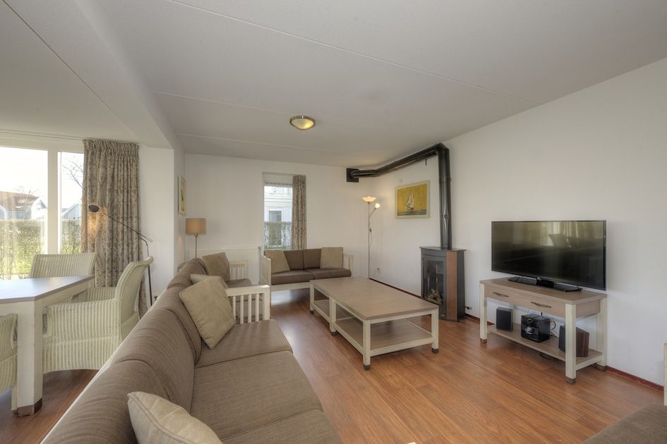 Gemuetliches Wohnzimmer des Ferienhauses Heerenhuys Comfort 14 in Bruinisse, Schouwen-Duiveland, mit bequemen Sofas und Holzofen.
