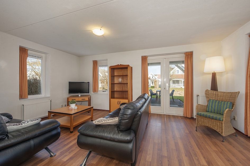 Cozy living room of Buitenhuis with sauna 6, vacation home in Bruinisse, Schouwen-Duiveland, with comfortable sitting area and garden view.