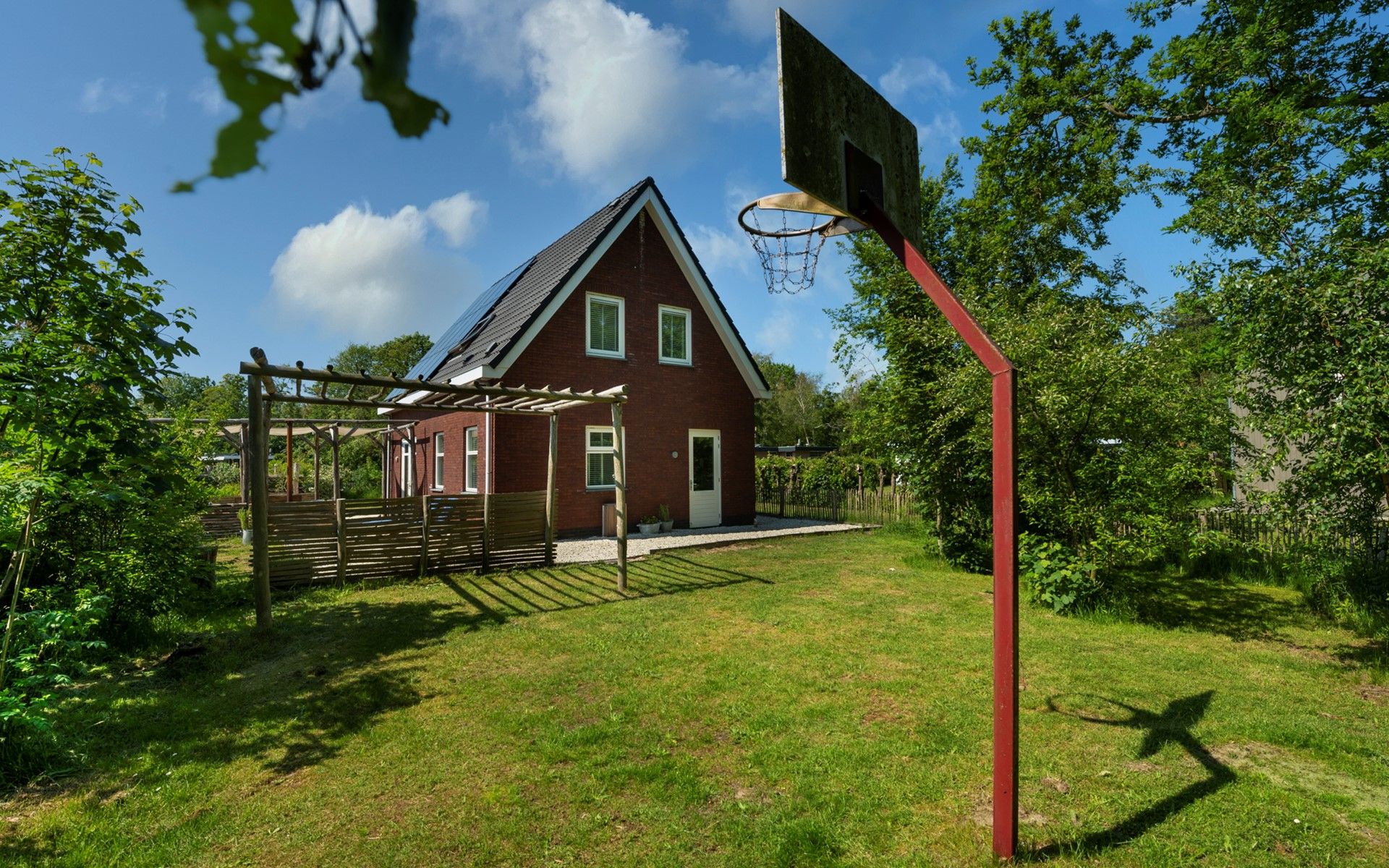Grosszuegige Rasenflaeche mit Basketballkorb im Ferienhaus De Zuidhoek 6 in Renesse, ideal fuer sportliche Aktivitaeten.