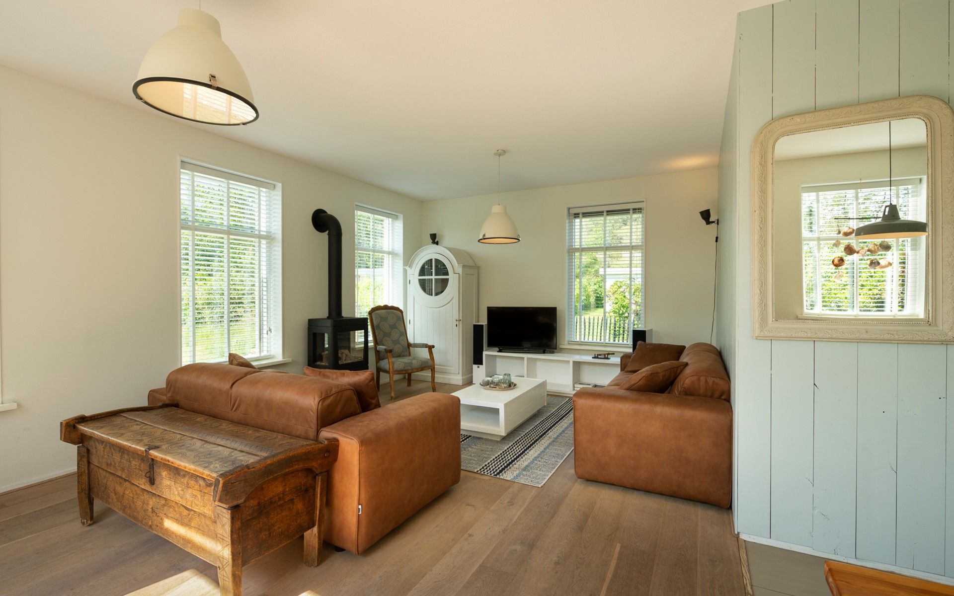 Geraeumiges Wohnzimmer im Ferienhaus De Zuidhoek 6 in Renesse, mit bequemen Sofas und Holzofen.