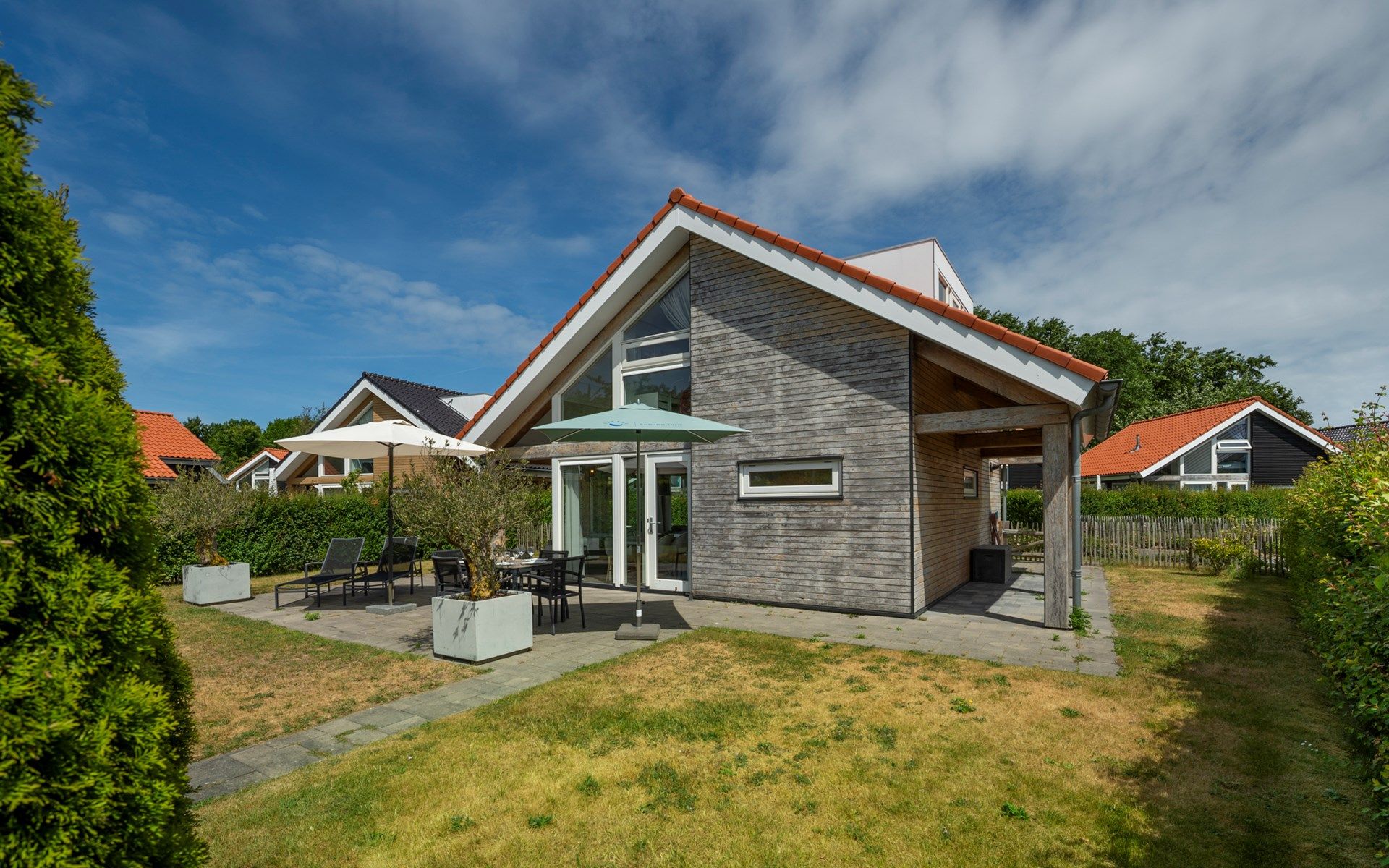 Gemuetlicher Aussenbereich des Ferienhauses Zonnedorp 8, De Zeehond in Renesse, Zeeland mit Sonnenschirmen.