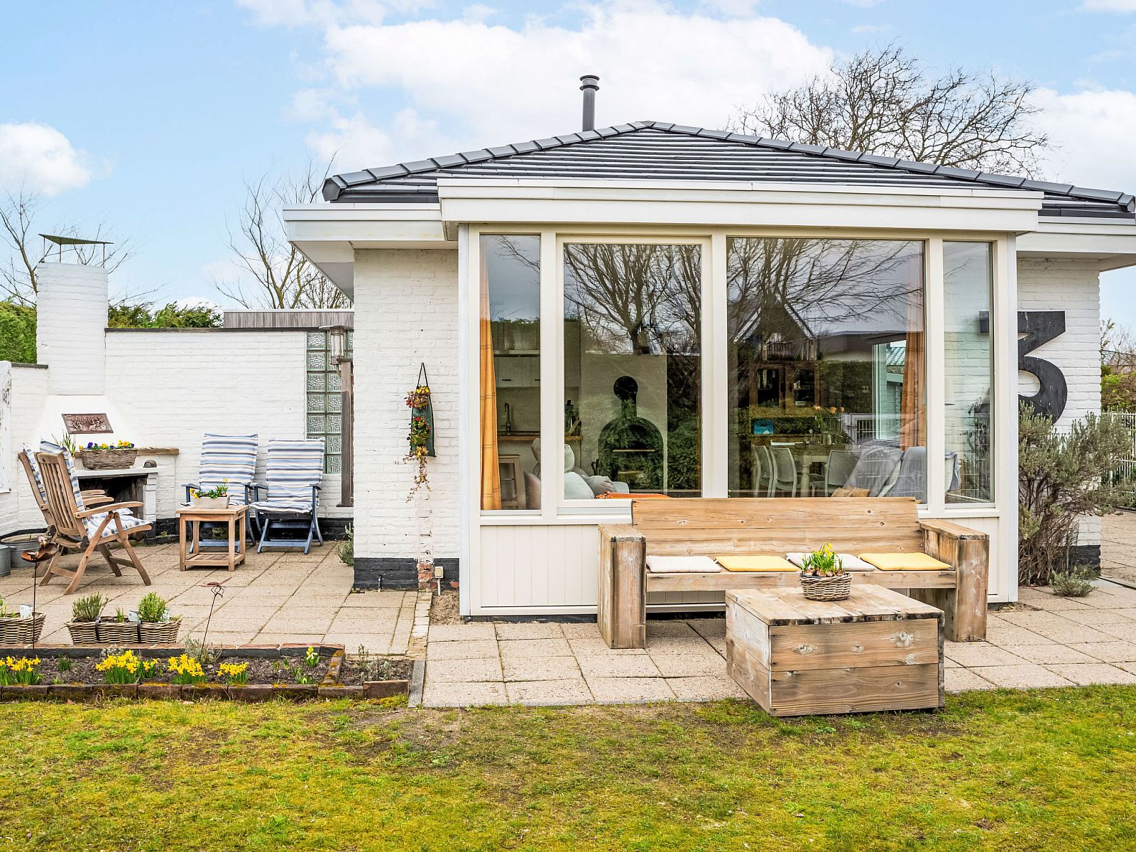 Vacation home Horizon by the Sea in Renesse, cozy terrace with wooden furniture and lots of greenery.